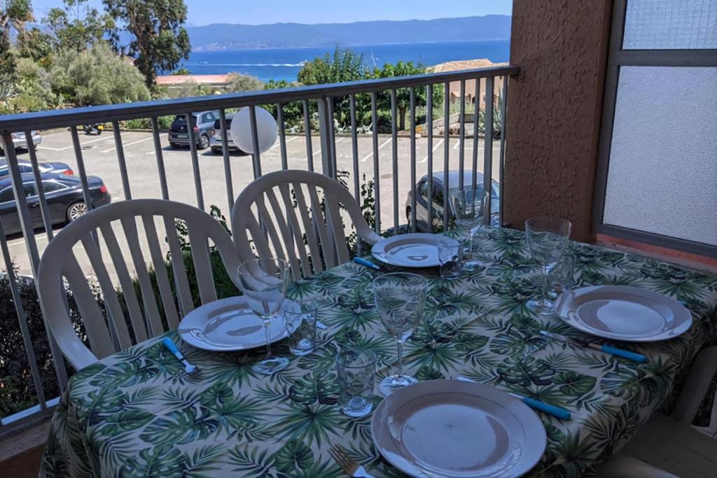 une table avec des assiettes et des verres sur un balcon dans l'établissement Studio 4 pers terrasse vue mer, à Ajaccio