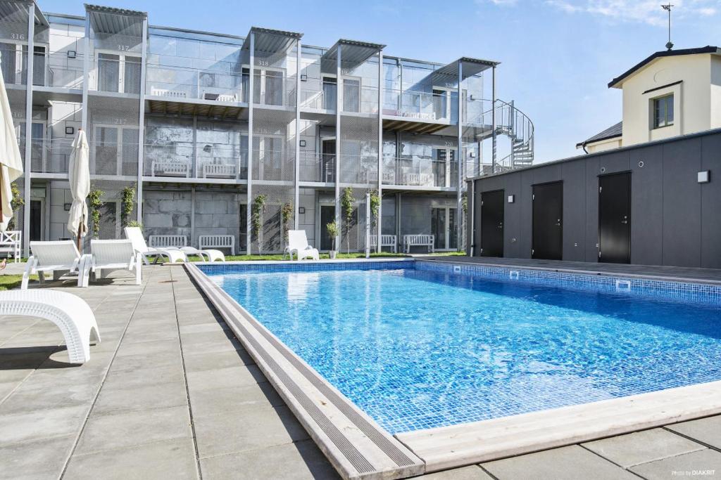 a swimming pool in front of a building at Kolgården - Visby Lägenhetshotell in Visby