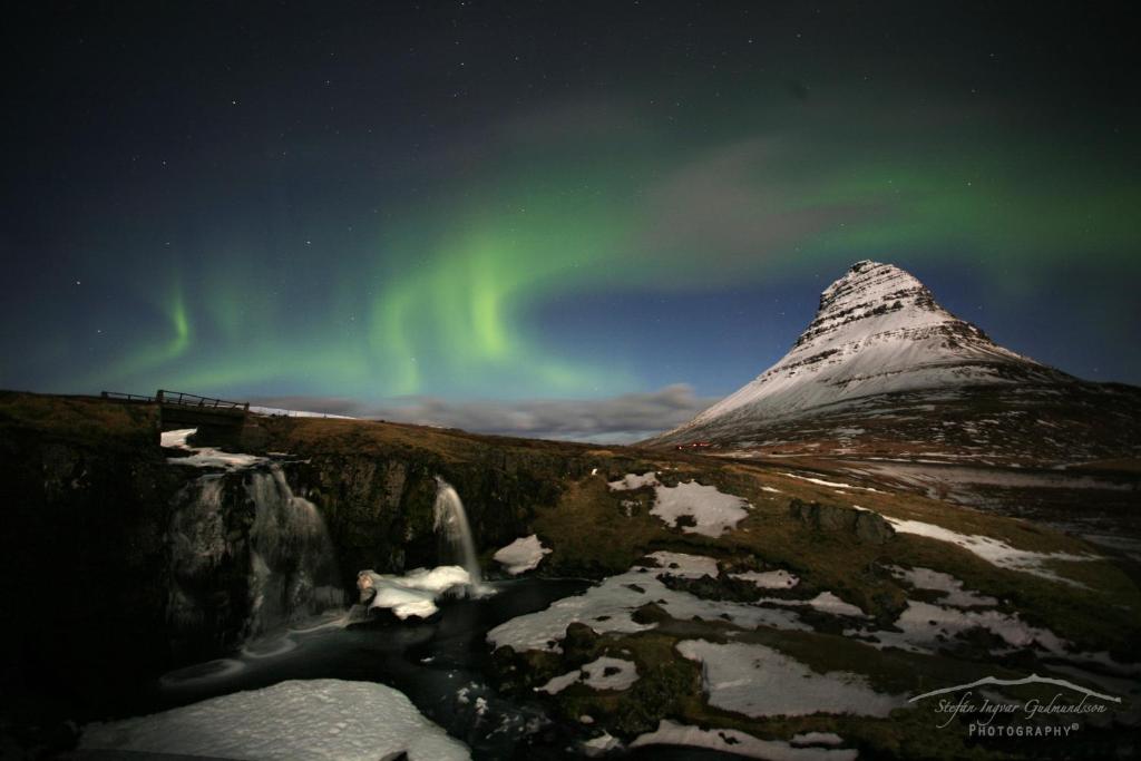 an image of a mountain with the aurora in the sky at Við Hafið Guesthouse in Ólafsvík