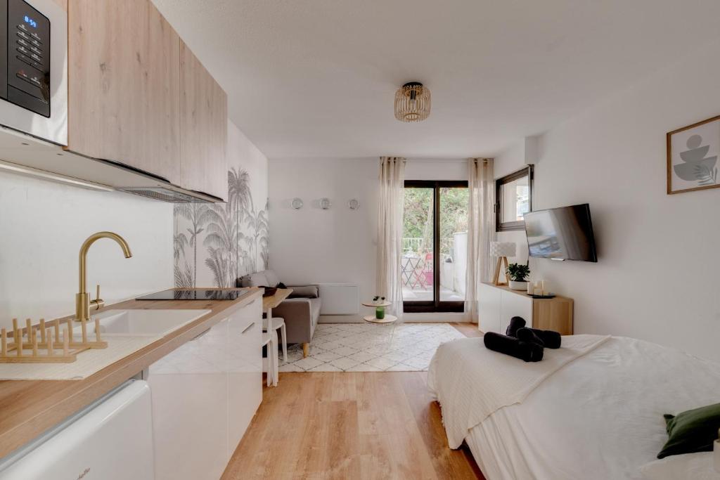 Il comprend une cuisine blanche avec un évier et un salon. dans l'établissement Studio Place Dupuy, clim, parking, terrasse, à Toulouse