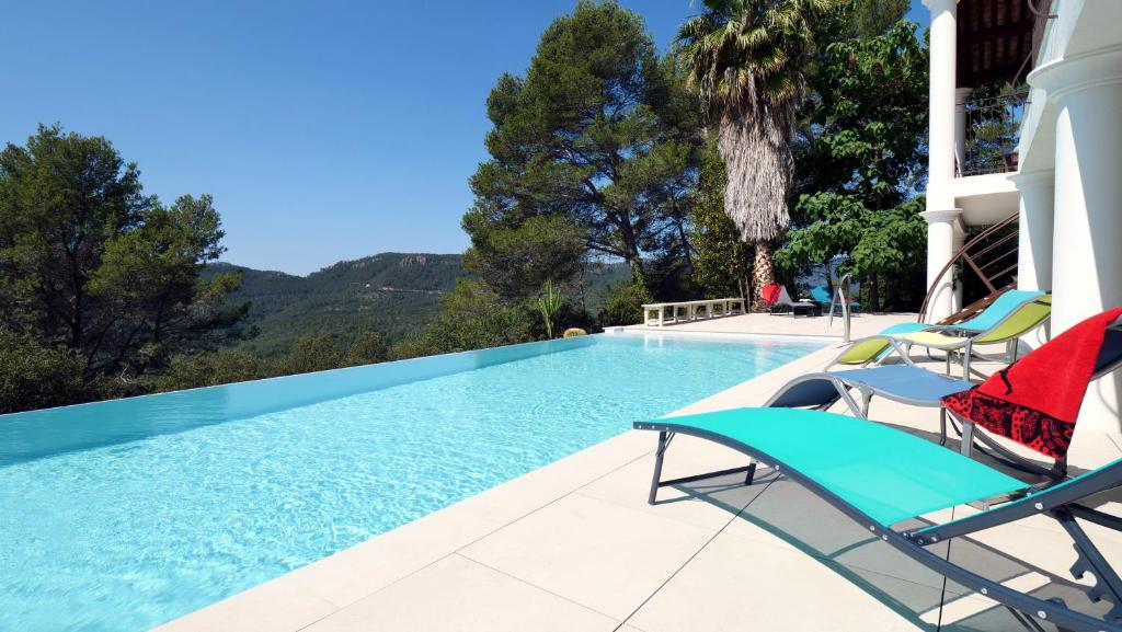 une piscine avec 2 chaises longues et une maison dans l'établissement Villa d'Eden domaineleshesperides, à Bagnols-en-Forêt