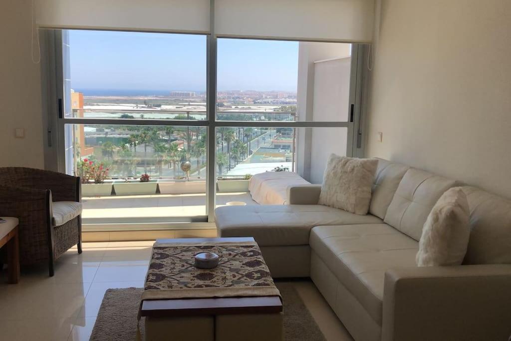 a living room with a white couch and a large window at Apartamento Deluxe: hidromasaje, terraza y vistas. in Las Hortichuelas