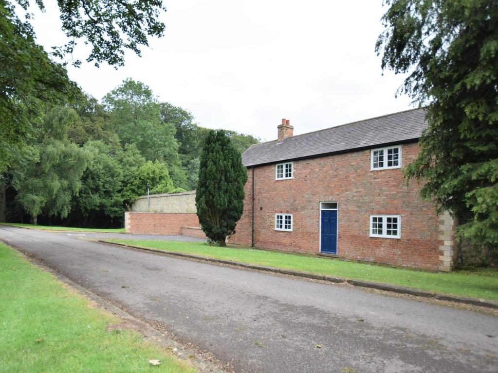 a brick house with a blue door on a road at 2 Bed in Ripon HH039 in Bishop Monkton
