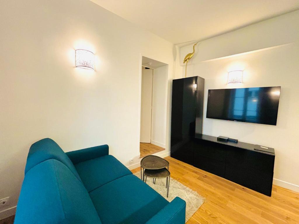 uma sala de estar com um sofá azul e uma TV de tela plana em Lovely studio in the Heart of St Germain-des-Prés em Paris