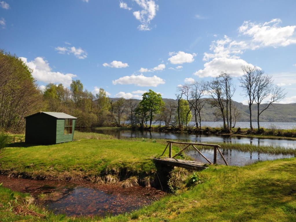 a small shack and a boat on the shore of a lake at 2 Bed in Loch Ness GRANY in Invermoriston