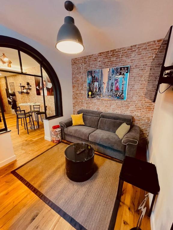 un salon avec un canapé et un mur de briques dans l'établissement HUDSON HIGHLANDS Annecy Rent Lodge, à Annecy