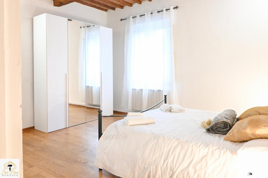 1 dormitorio blanco con 1 cama grande y espejo en Inn Pisa Rentals - Rustic Style Flat, en Pisa