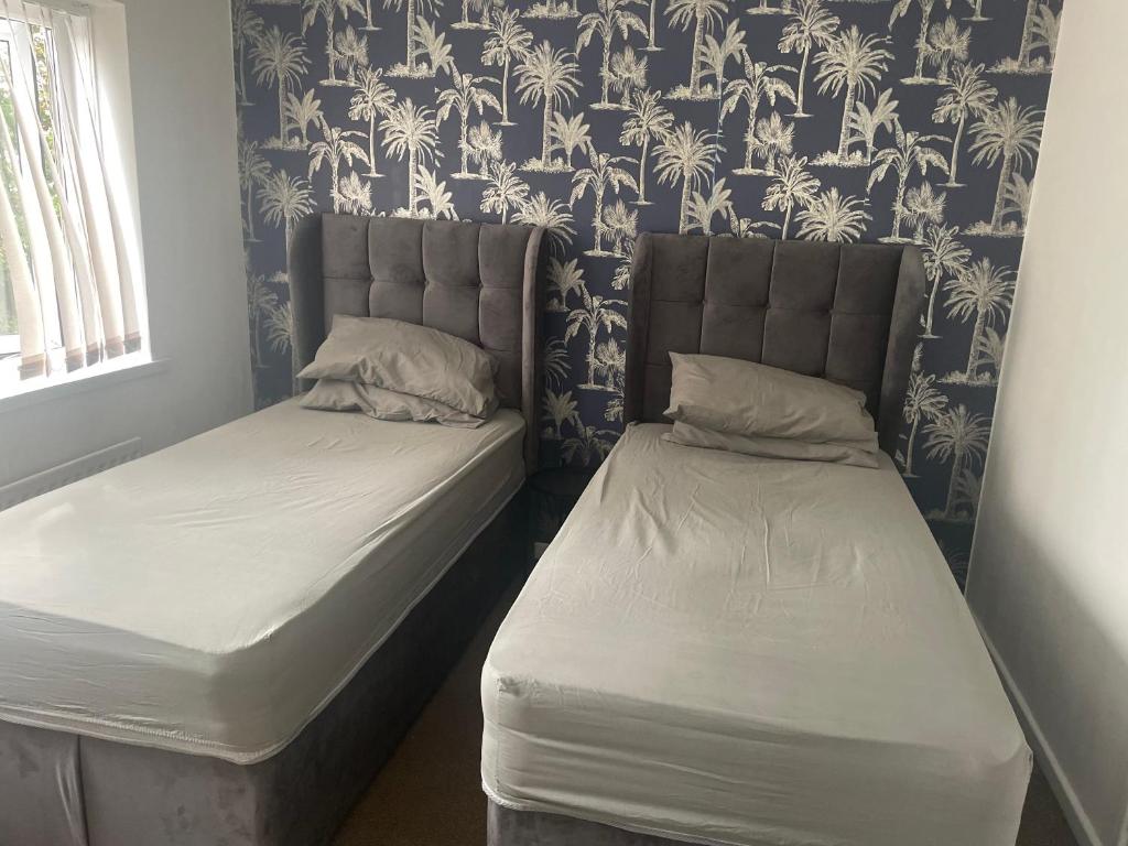 two beds in a room with blue and white wallpaper at 4 Bed Comfy House in Birmingham in Birmingham