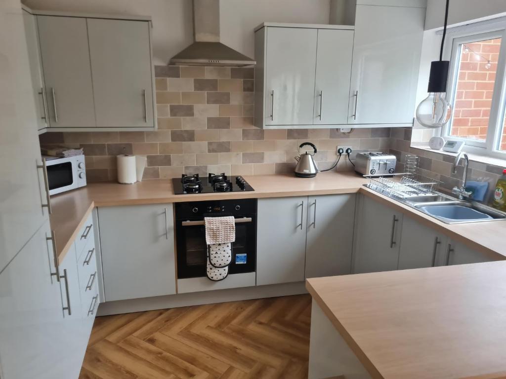 a kitchen with white cabinets and a stove top oven at 5Bed House Wirral near Liverpool Chester in Wirral