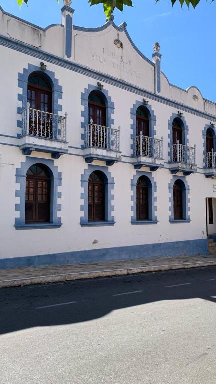 a white building with windows and balconies on a street at Pousada Economic Pitangui in Pitangui