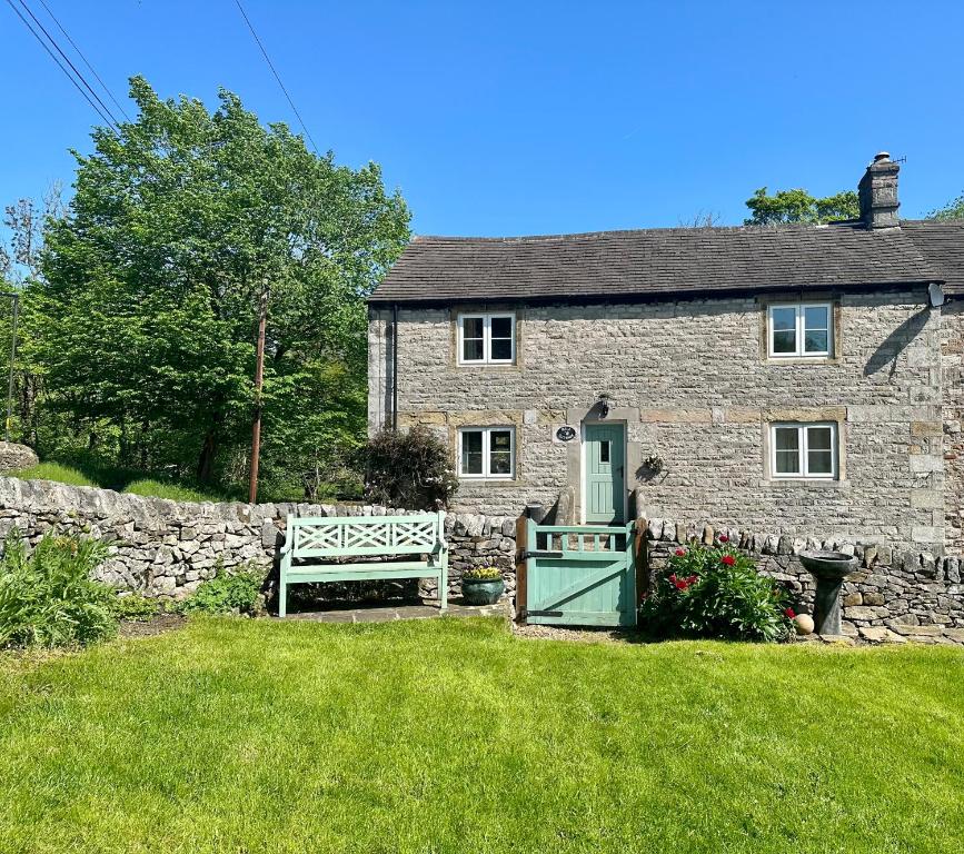 ein Steinhaus mit grüner Tür und einem Zaun in der Unterkunft Mill Cottage in Hope