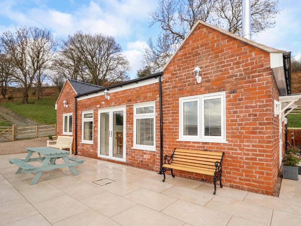 a brick house with a bench and a picnic table at Border View Lodge in Welshpool