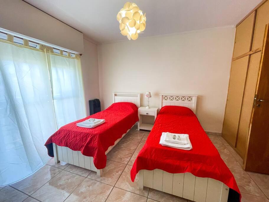 1 dormitorio con 2 camas con sábanas rojas y lámpara de araña en Namuncura 646 by depptö en Bahía Blanca