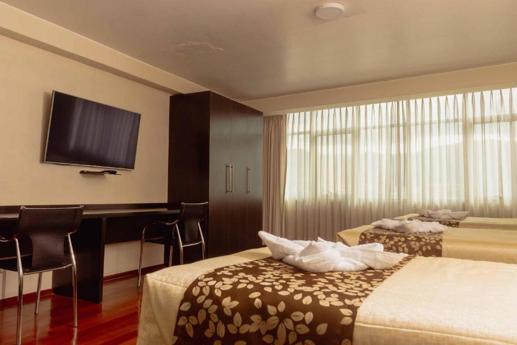 Habitación de hotel con 2 camas y escritorio en Group House Apart Hotel, en Cusco