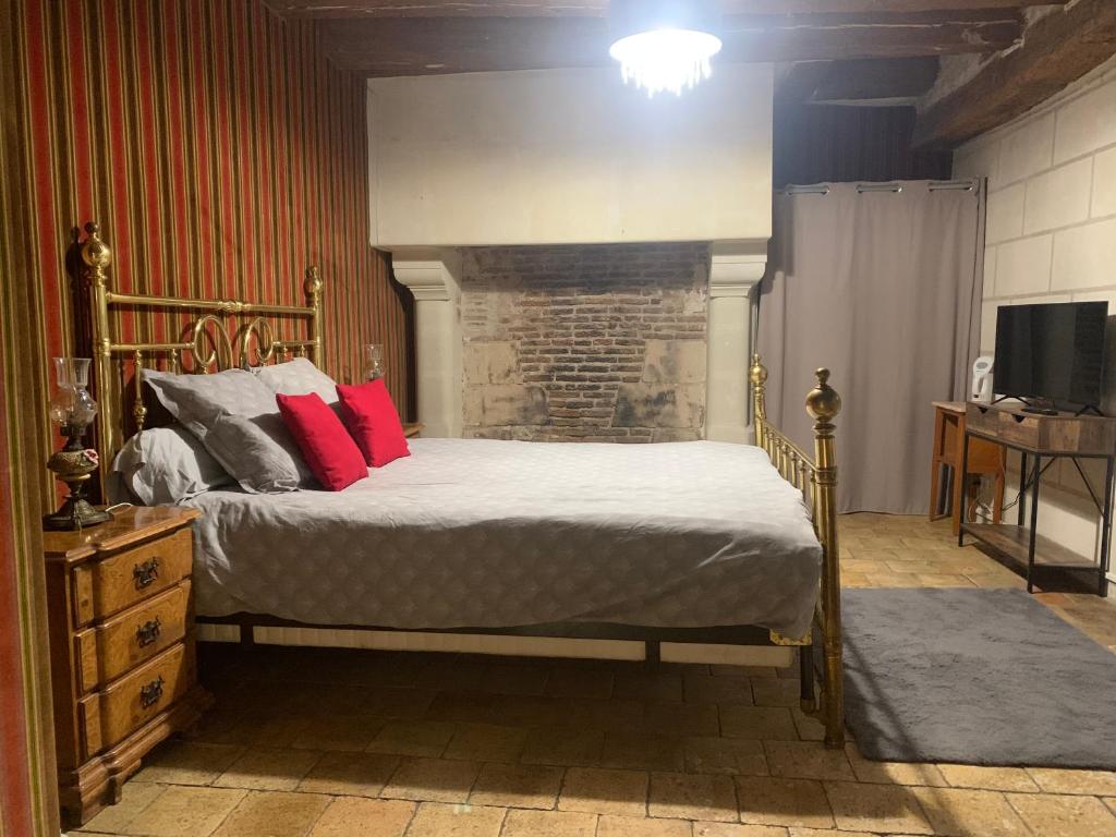 1 dormitorio con cama con almohadas rojas y chimenea en La Grange d Ave, en Luynes