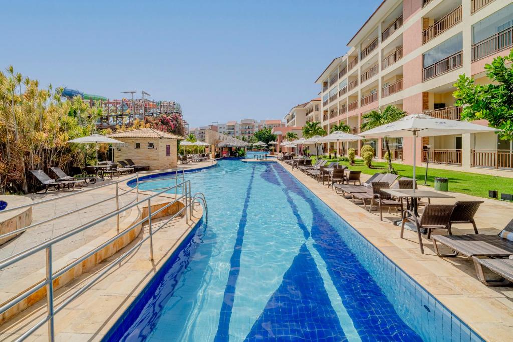 a swimming pool with chairs and tables in a hotel at Beach Park Resort - Wellness in Aquiraz