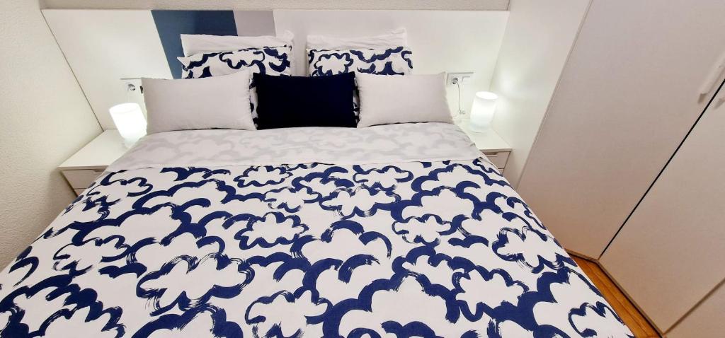 1 cama con edredón y almohadas azules y blancos en Habitacion de lujo *Baño Privado* Zona Centro en Madrid