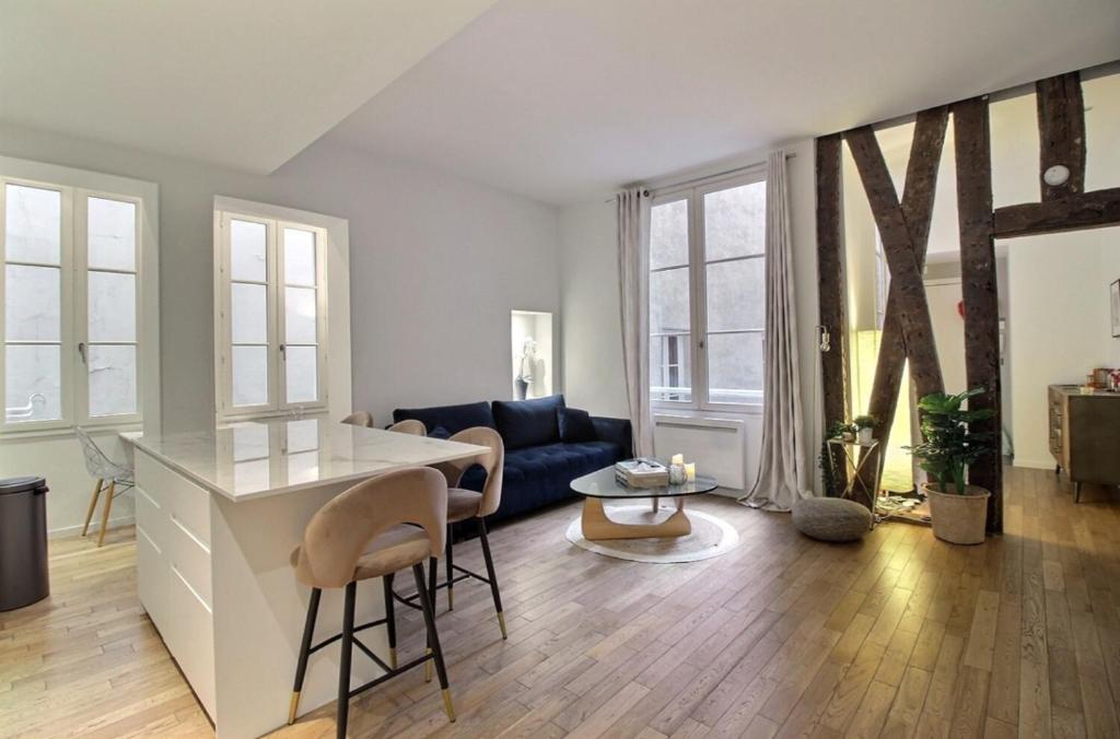 een keuken en een woonkamer met een blauwe bank bij APPARTEMENT PARIS - LOUVRE & RIVOLI in Parijs