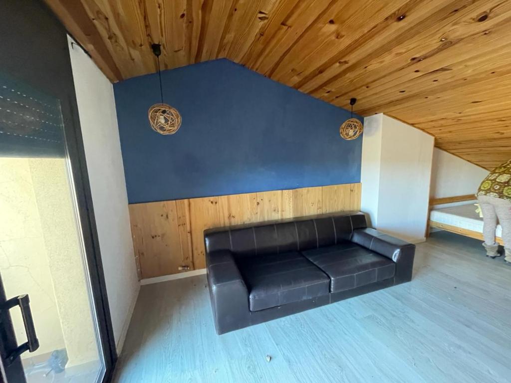 Sofá negro en una habitación con techo de madera en La Mar de Palamós Suite, en Palamós