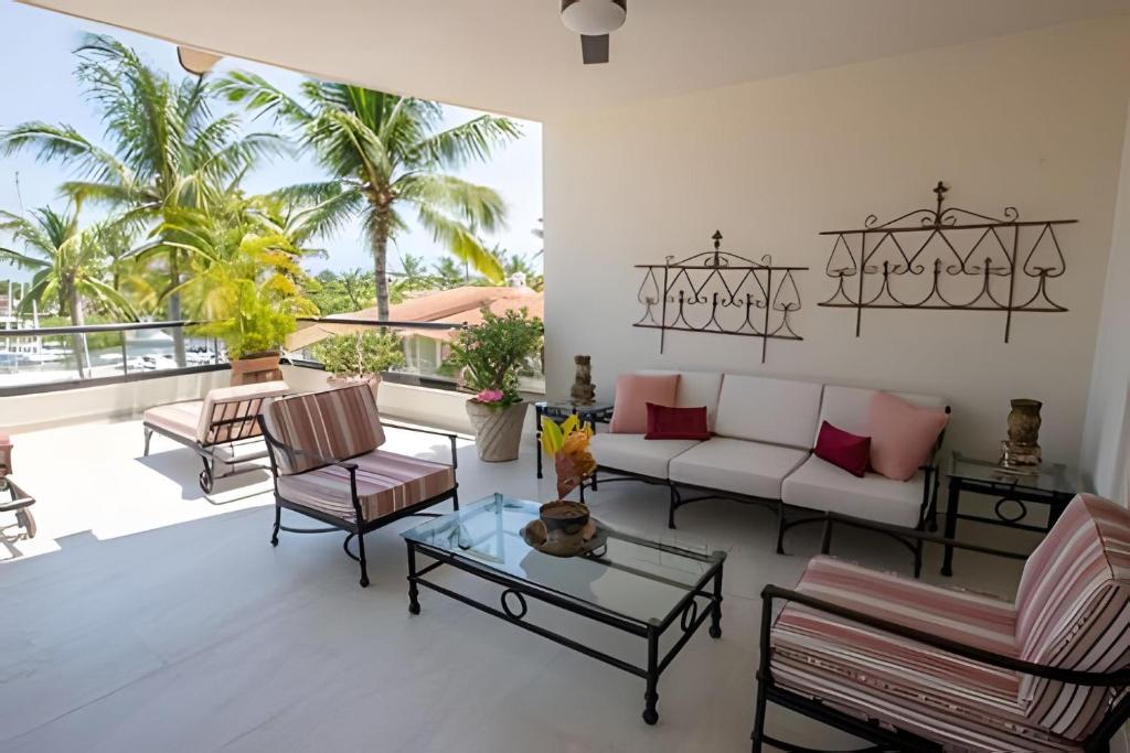 a living room with a couch and chairs and palm trees at Grand Marina Villas in Nuevo Vallarta 