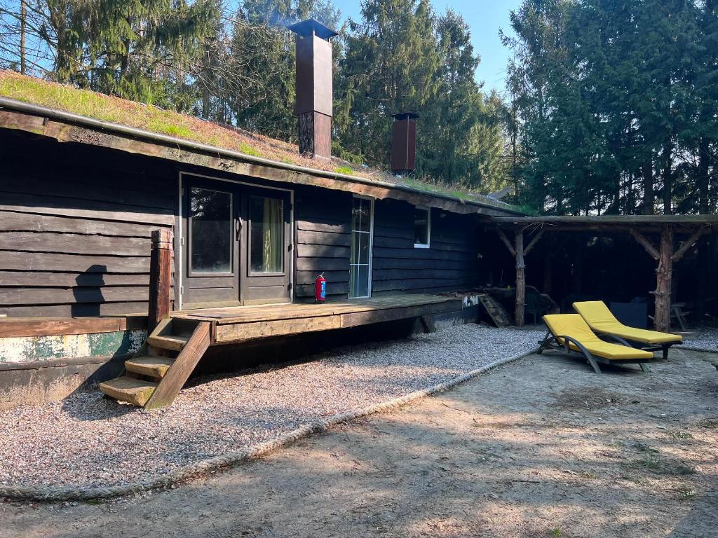 ein Blockhaus mit einer Veranda und zwei gelben Stühlen in der Unterkunft Gestrande Woonark in Erica