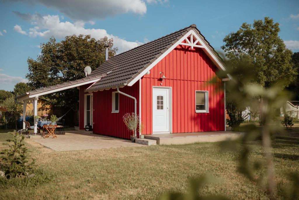 eine rote Scheune mit einer weißen Tür und einer Terrasse in der Unterkunft Ferienhaus Vandra in Eisenach