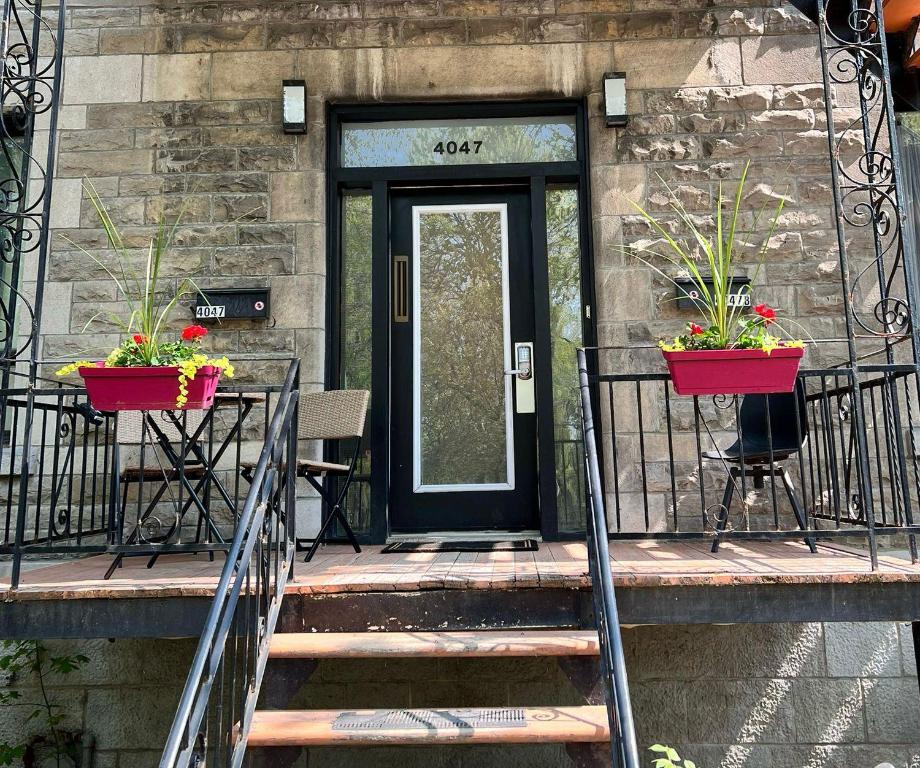 une porte d'entrée d'un bâtiment avec deux plantes en pot dans l'établissement Private room & Private bathroom in le Plateau, à Montréal