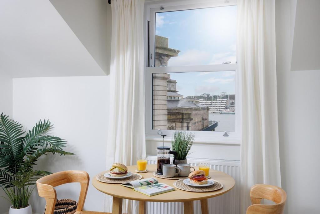 uma mesa com comida numa sala com uma janela em 2 Bed - Penthouse The Gatehouse by Pureserviced em Plymouth