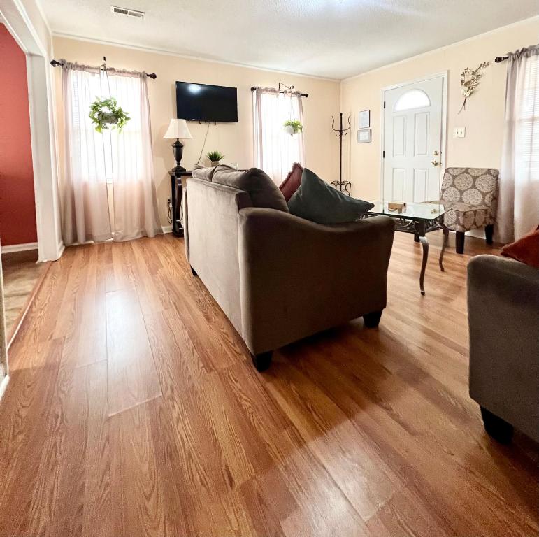 uma sala de estar com 2 sofás e um piso de madeira em A Cozy Spot on Montague em Charleston