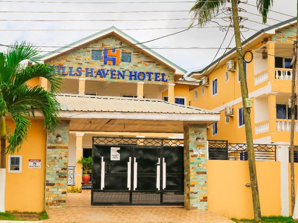 a yellow hotel with a sign that reads his hawker hotel at HILLS HAVEN HOTEL in Accra