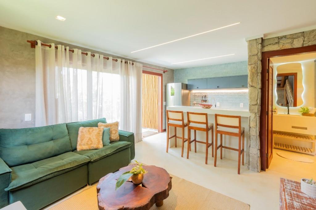 sala de estar con sofá verde y cocina en Villa Meraki, en Pipa