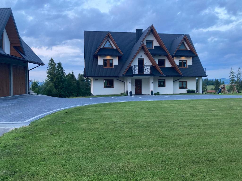 a house with a black roof and a green yard at PRZY LESIE in Bukowina Tatrzańska