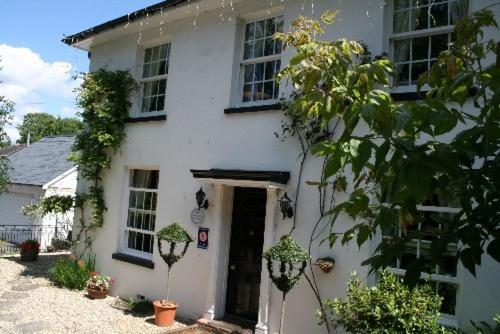 a white house with a door and some plants at Clayhill House Bed & Breakfast in Lyndhurst