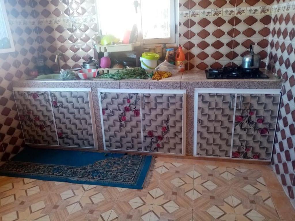 eine Küche mit einer Spüle und einer Theke mit Geschirr in der Unterkunft Dar El Ghali in Er Rachidia