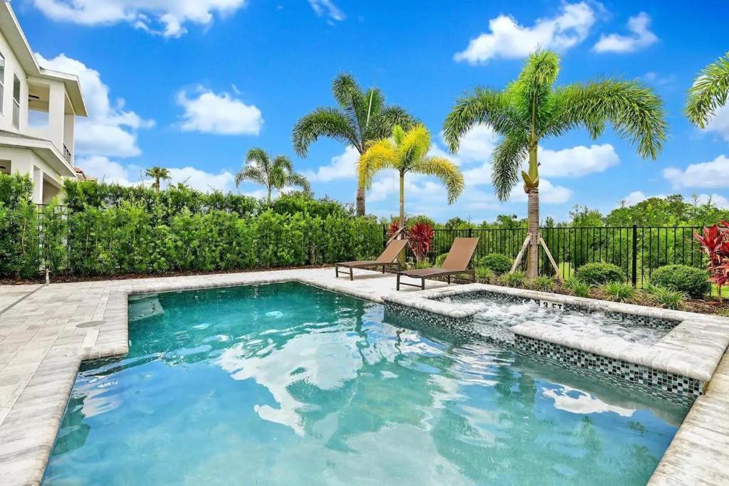 - une piscine avec 2 chaises et des palmiers dans l'établissement Exclusive Resort- House Sleeps 18. 1117, à Kissimmee