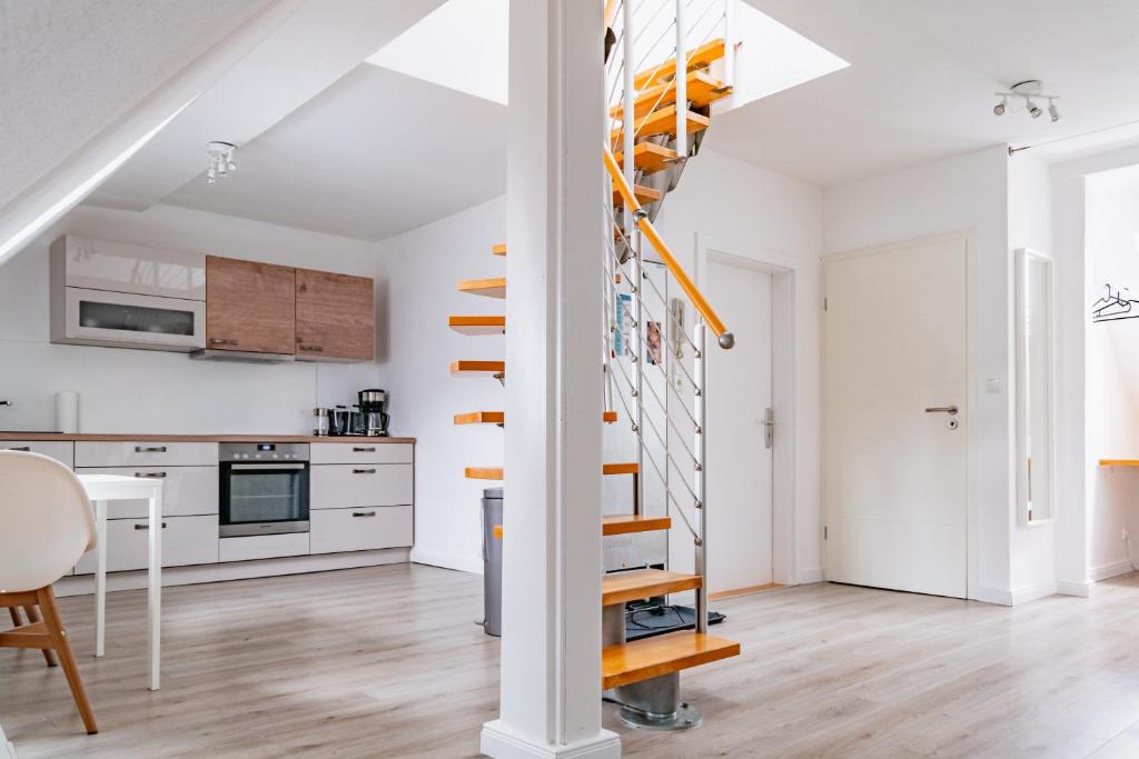 eine weiße Küche mit einer Wendeltreppe in einem Apartment in der Unterkunft Maisonettewohnung Küstenliebe in zentraler Lage in Rostock