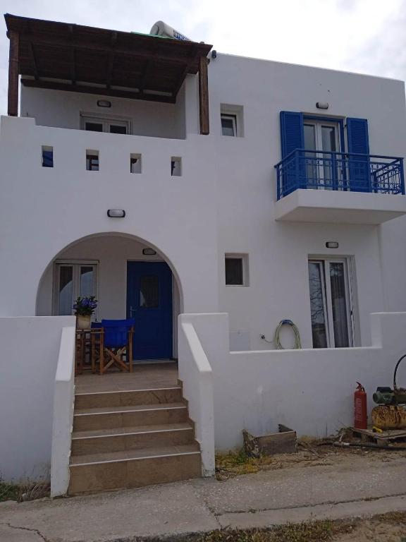 a white house with a blue door and stairs at SOHOROS STUDIOS in Irakleia