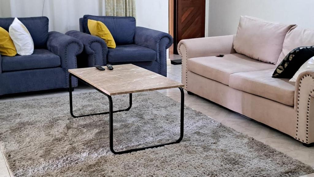 uma sala de estar com dois sofás e uma mesa de centro em Tamiasuites Apartment em Kisumu