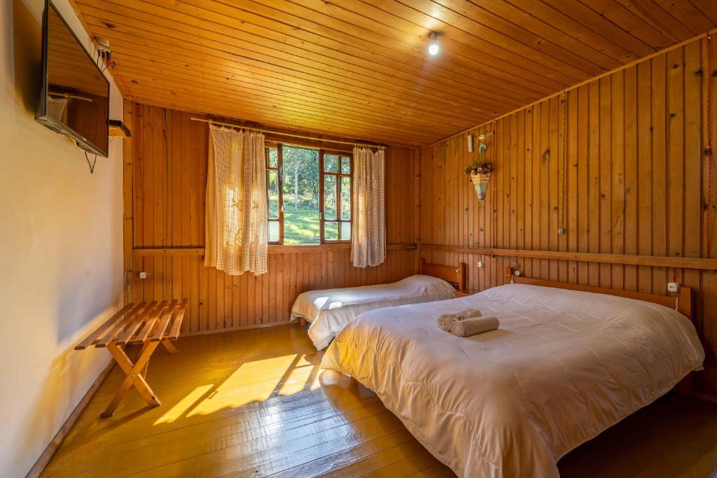 um quarto com 2 camas num chalé de madeira em Pousada Morro Grande em Bom Jardim da Serra