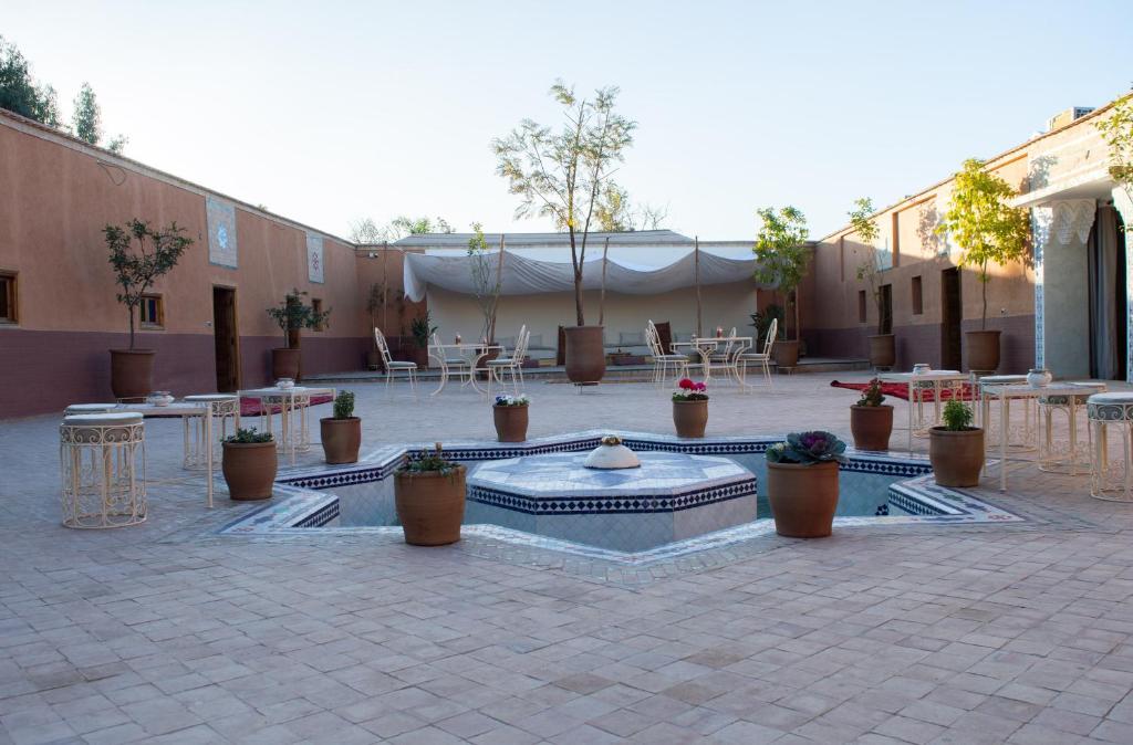un patio con una fuente, mesas y macetas en Ferme D'hôte Zomorroda en Marrakech
