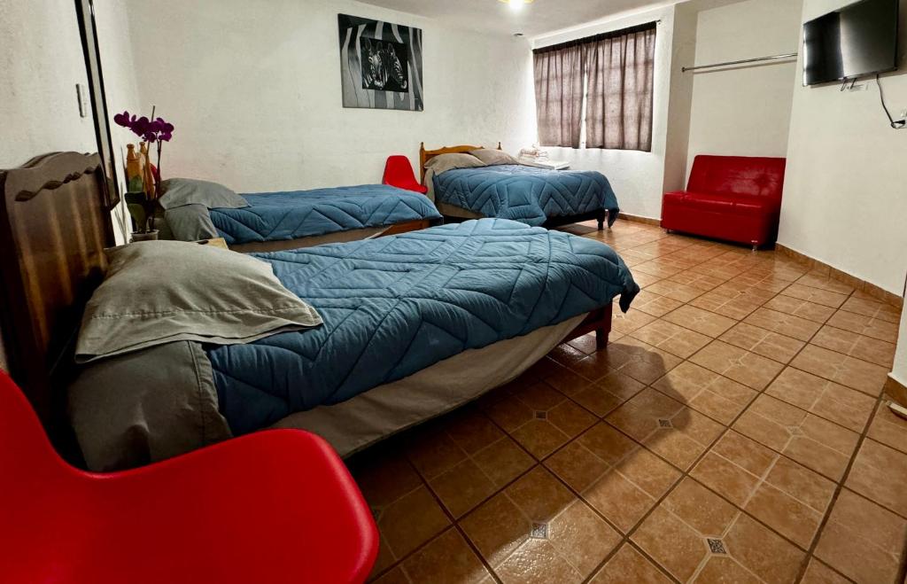 Habitación con 2 camas y silla roja. en Pura Vida! Ciudad Hidalgo en Ciudad Hidalgo