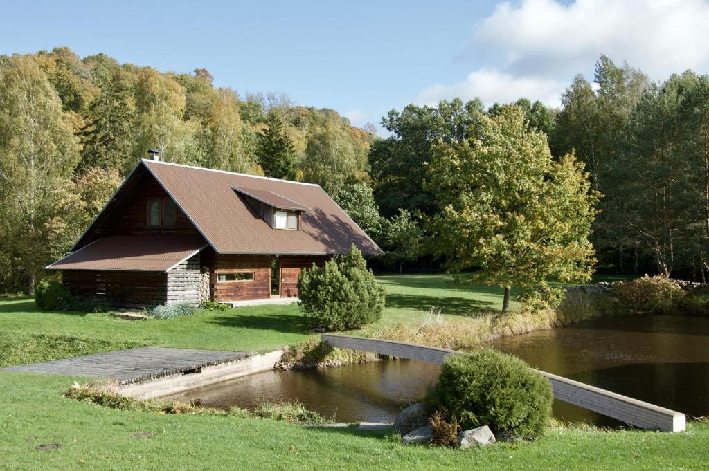 a log cabin with a pond in front of it at Užukalnio sodyba in Užuguostis