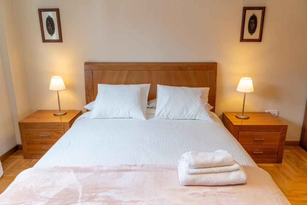 a bedroom with a bed with two lamps and towels on it at Apartamento Mayte in Siero