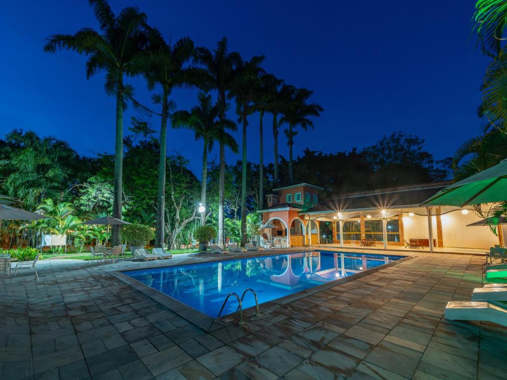 an exterior view of a resort pool at night at Carlton Suítes Limeira in Limeira