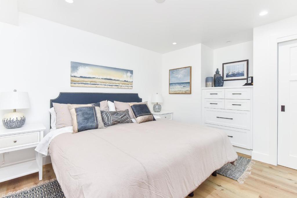 a white bedroom with a large bed with pillows at BRAND NEW Luxury 1 Bedroom Condo Steps from the Beach in Newport Beach