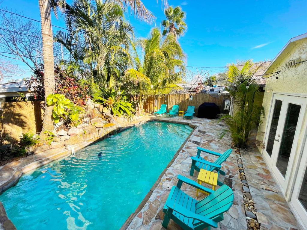 a swimming pool with blue chairs in a backyard at Laguna Azul - Sleeps 8 + Heated Pool + Walk to Beach in St Pete Beach