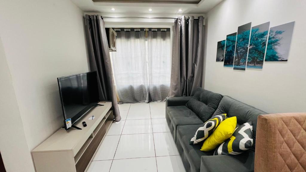 Apartamento Home Pratice في ساو لويس: غرفة معيشة مع أريكة وتلفزيون بشاشة مسطحة