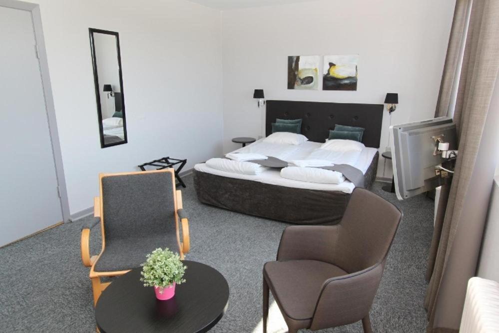 um quarto com uma cama, uma mesa e cadeiras em Banegaardshotellet em Vojens