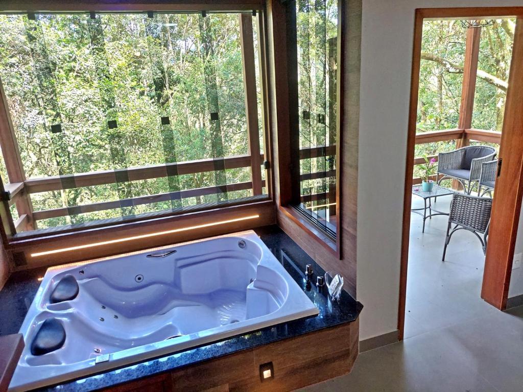 una grande vasca da bagno in una camera con due finestre di Pousada Aquarela - Macacos a Macacos