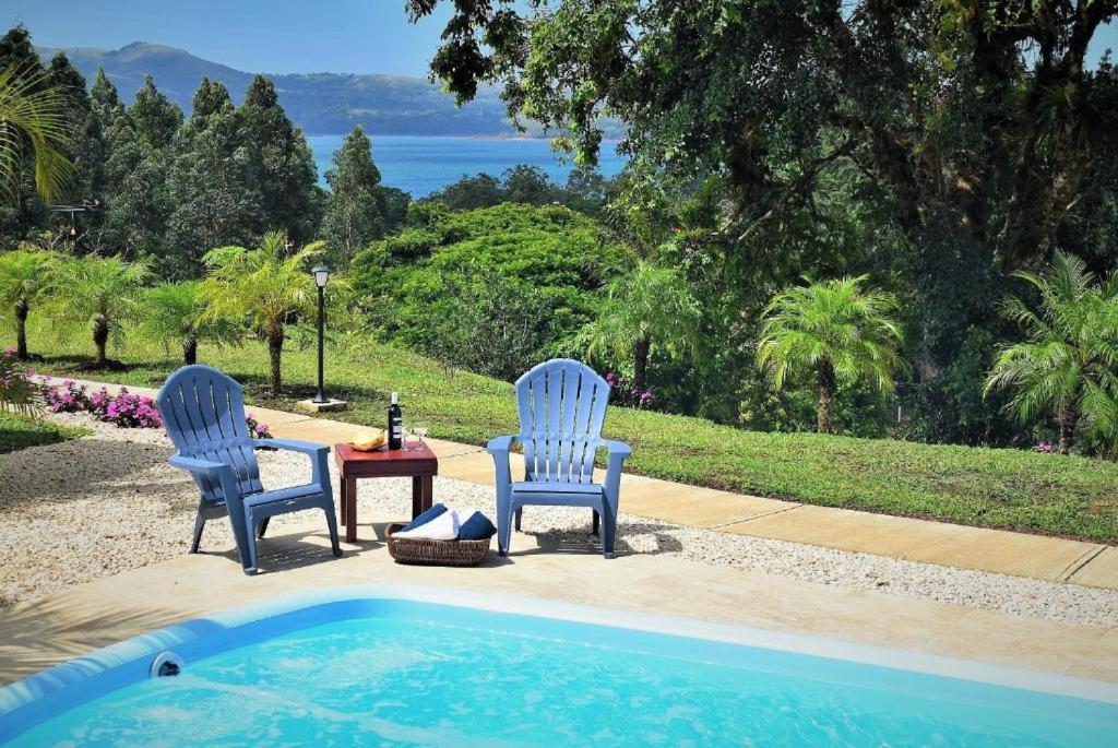 two chairs and a table next to a swimming pool at Arenal Villas Tranquilas, free-standing equipped houses in Nuevo Arenal